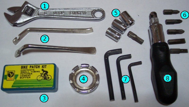 A numbered assortment of basic bicycle repair tools including tire levers, hex keys, sockets, a spoke wrench, and an adjustable wrench